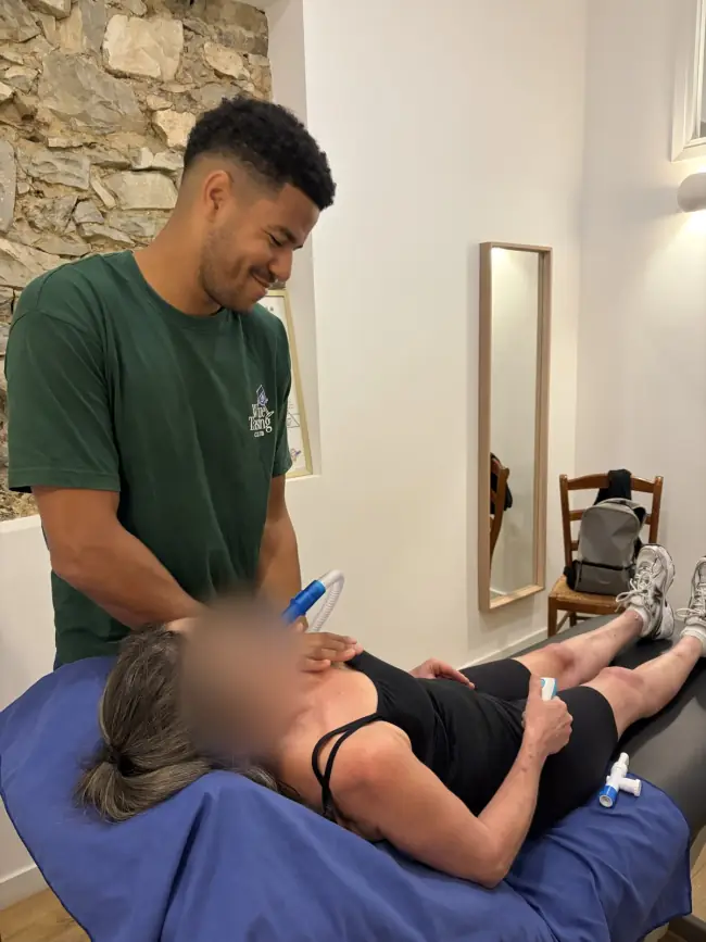 Un kinésithérapeute accompagne une patiente allongée
